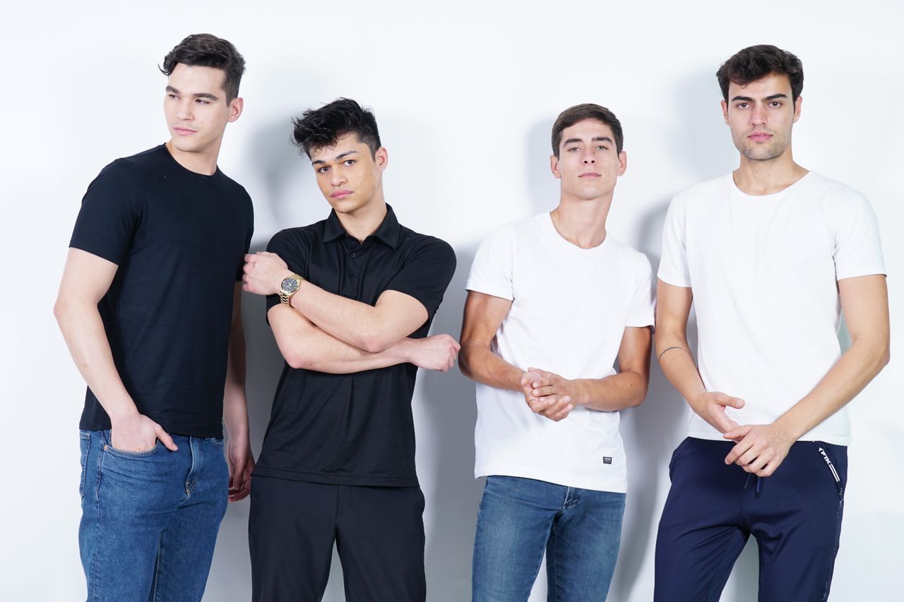team-04 Group of four young men in casual outfits posing in studio with white background.