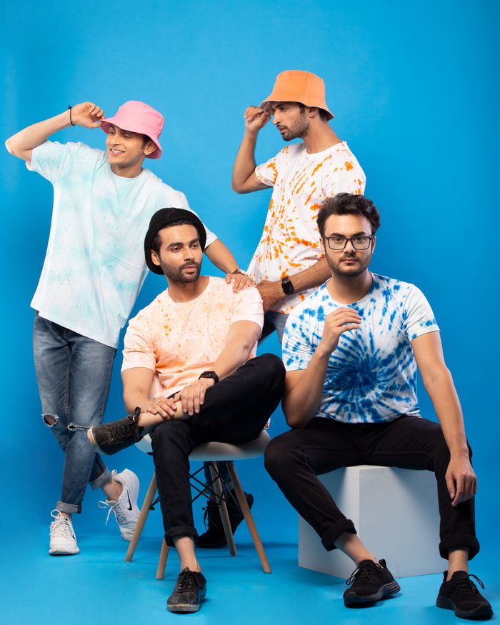 team-01 A stylish group of men posing in colorful tie-dye T-shirts in a studio setting.