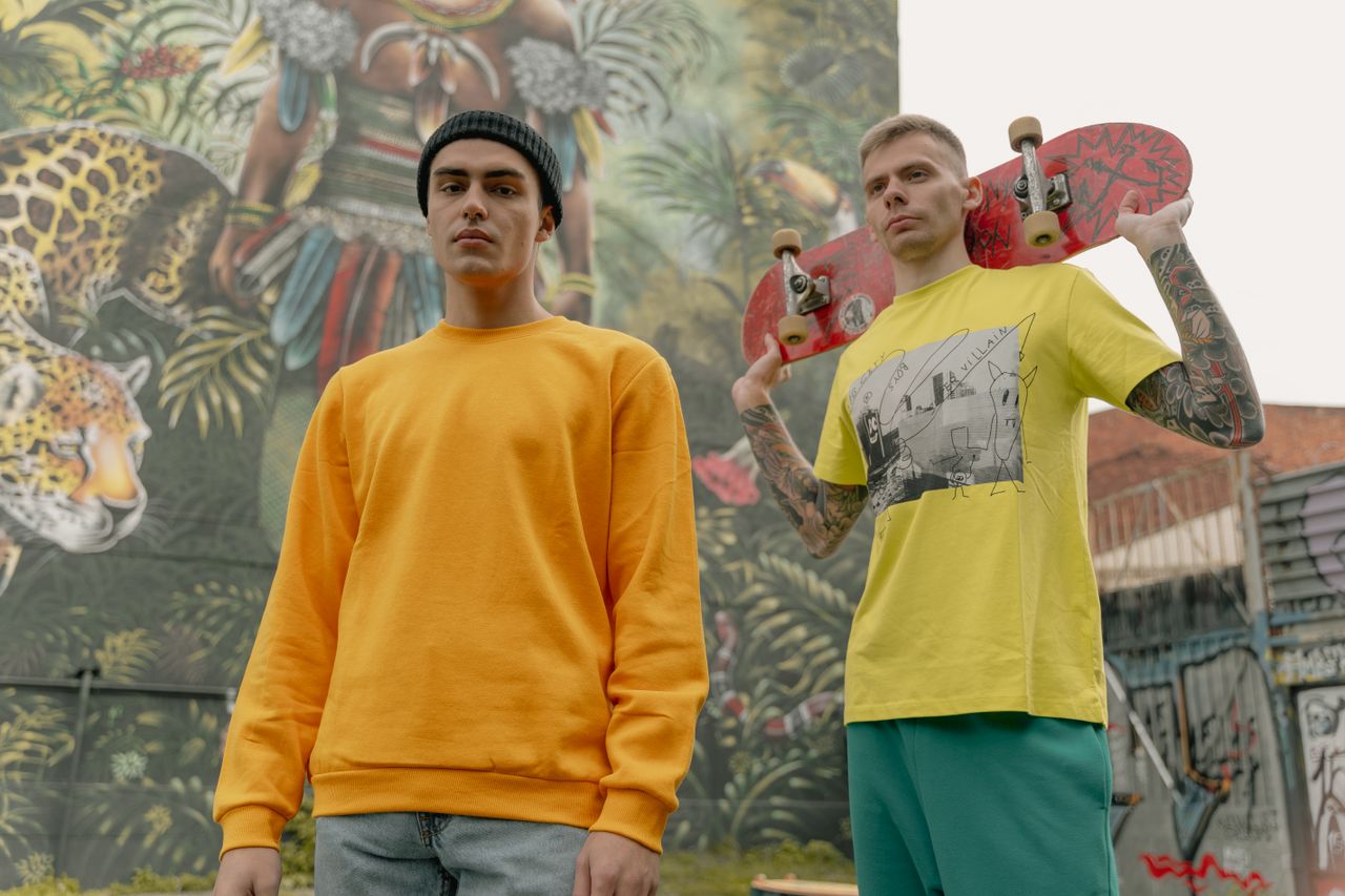 Crafting Captivating Headlines: Your awesome post title goes here Two fashionable men posing with skateboards in front of a vibrant mural.